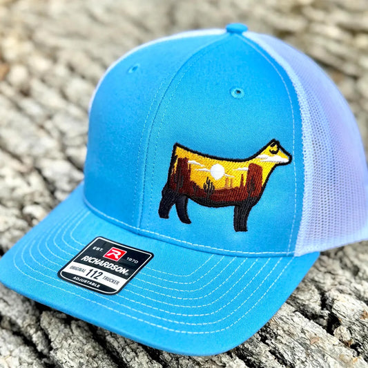 Embroidered hat of a desert scene in the silhouette of a show heifer