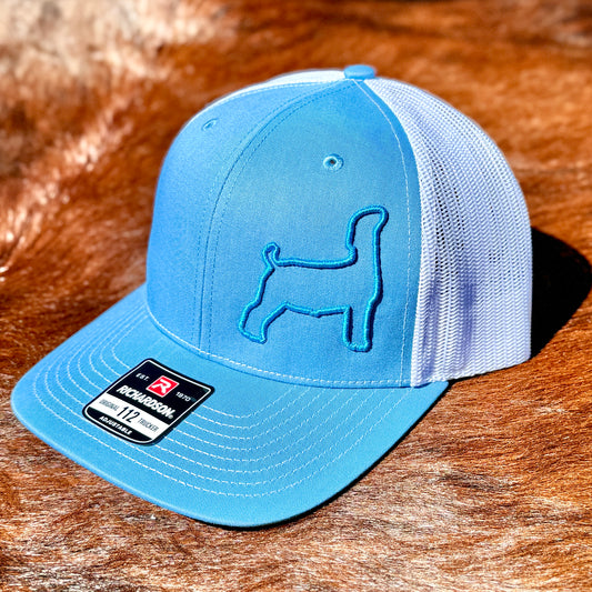 Blue and white trucker cap featuring a raised 3D embroidered outline of a market goat.