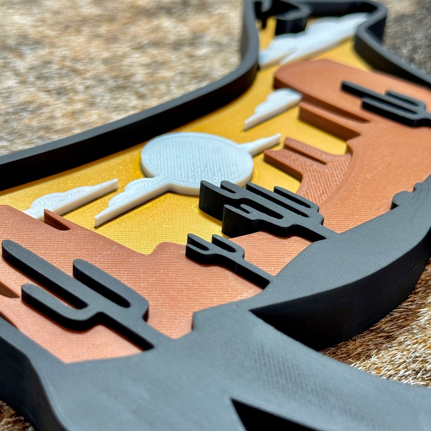 Close-up of a decorative 3D printed sunset heifer sign with abstract shapes on a textured surface