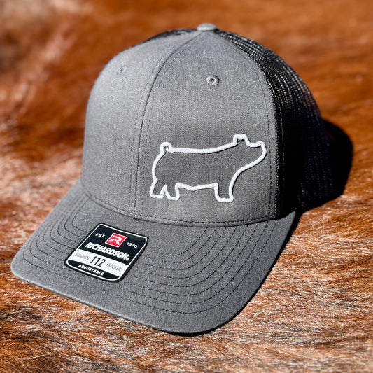 Dark grey trucker hat featuring raised 3D embroidered outline of a show pig.