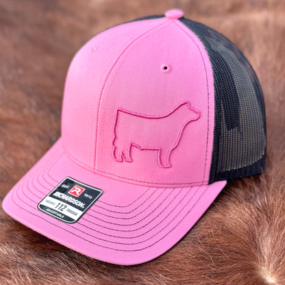 Pink and black hat featuring a raised 3D embroidered design of a pink outline of a show steer.