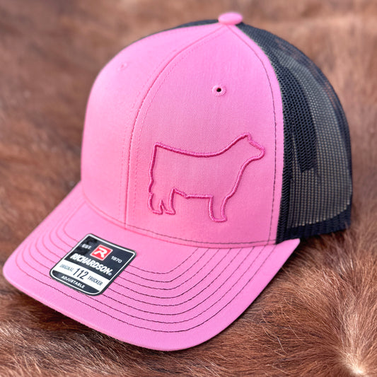 Pink and black hat featuring a raised 3D embroidered design of a pink outline of a show steer.