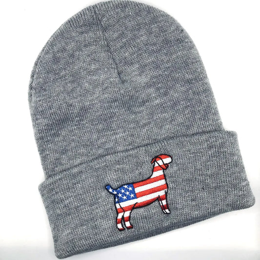 A grey knit beanie with an embroidered patch of a goat silhouette featuring an American flag design, with red and white stripes and a blue field with white stars. The beanie has a folded cuff and is laid flat on a white background.