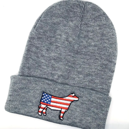 A gray knit beanie with an embroidered show steer patch featuring the American flag design. The steer silhouette is outlined in black, with red and white stripes on the body and a blue field with white stars on the front. The beanie has a folded cuff and is laid flat on a white background.