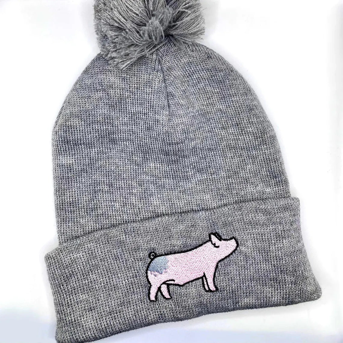 Comfortable and warm winter beanie hat featuring an embroidered design on a blue butt show pig.