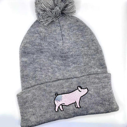 Comfortable and warm winter beanie hat featuring an embroidered design on a blue butt show pig.
