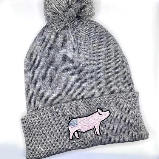 Comfortable and warm winter beanie hat featuring an embroidered design on a blue butt show pig.