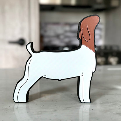A goat-shaped tabletop decoration made of PLA plastic, featuring a white body with a brown head and ears. The design is outlined in black for a bold, clean look. The goat stands on a light-colored countertop, with a modern kitchen in the background, including a stove and tiled backsplash.