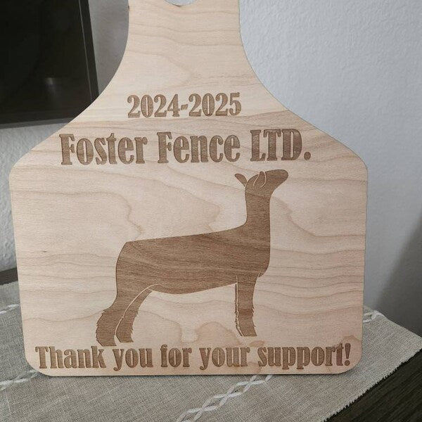 Wooden ear tag with engraved text and dog silhouette, featuring 'Foster Fence LTD.' and 'Thank you for your support!'.