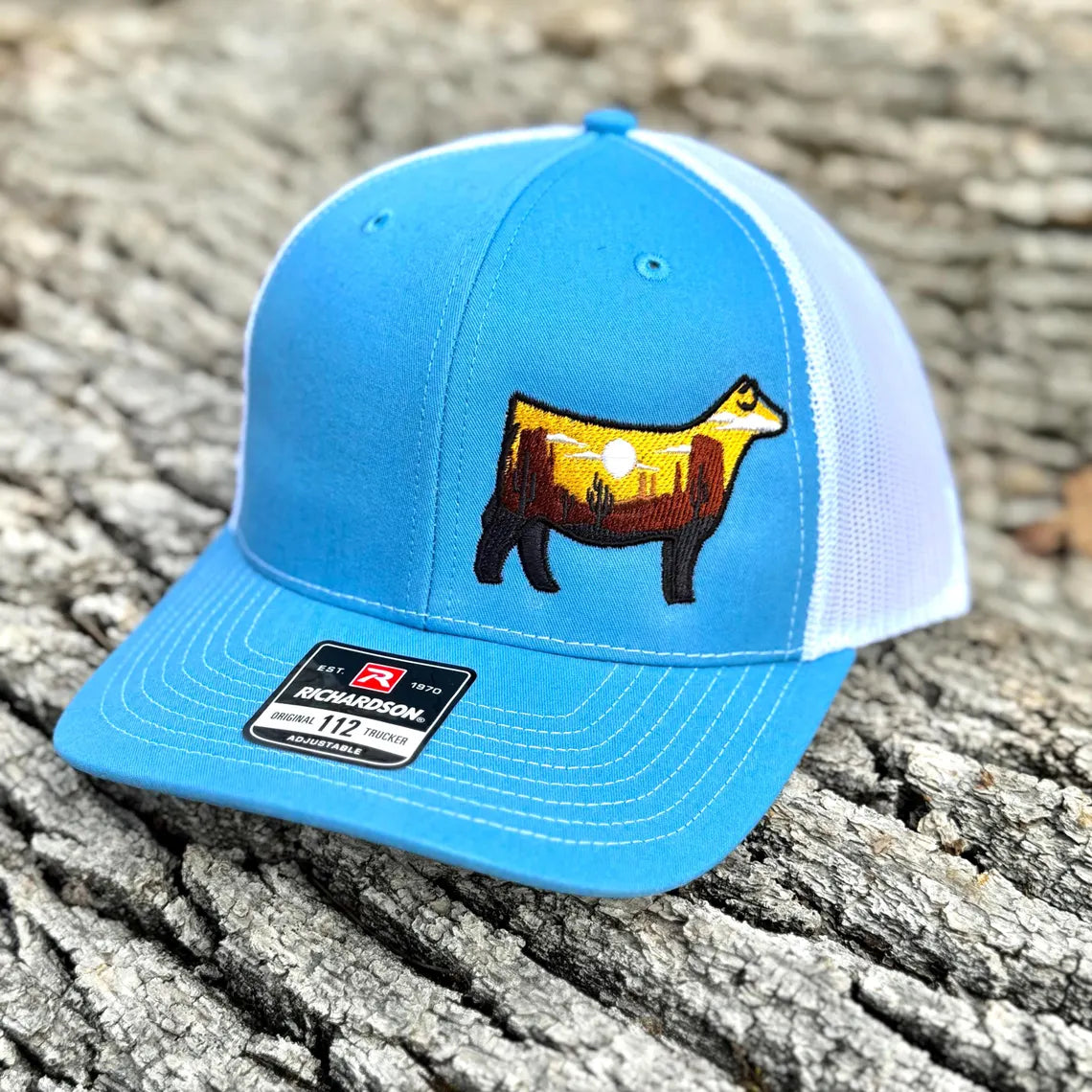 Embroidered hat of a desert scene in the silhouette of a show heifer