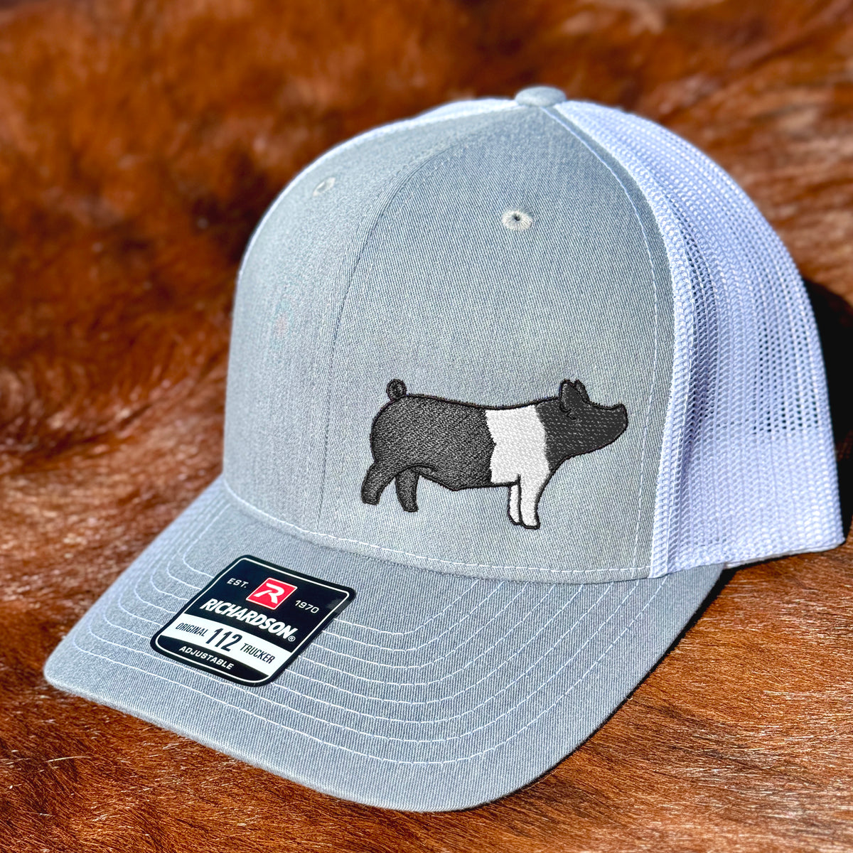 Grey and white cap featuring detailed embroidery of a Hampshire show pig.