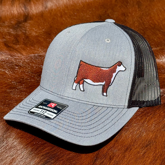 Heather grey and black Richardson 112 hat featuring an embroidered design of a red and white Hereford heifer.