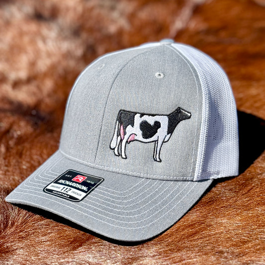 Grey hat with an embroidered design on a black and white Holstein cow.