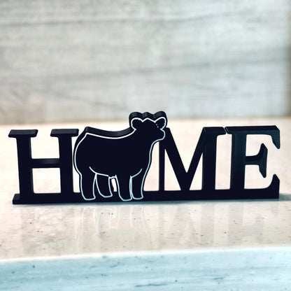 Freestanding tabletop or shelf decor reading the word "Home" with a show steer replacing the "O". Perfect for show cattle enthusiasts or those who love farmhouse decor.