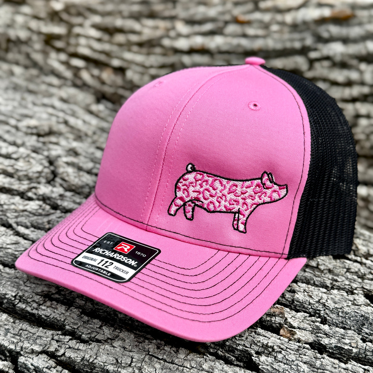 Pink cap with a pink leopard print show pig design on a wooden surface