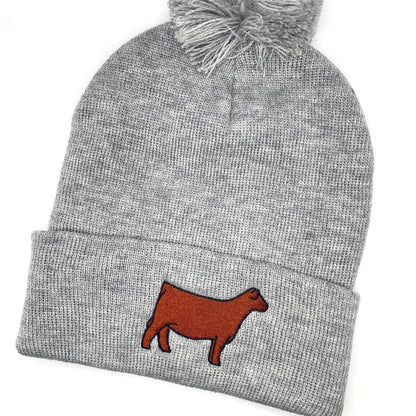 Comfy winter beanie hat with a pompom and high quality embroidery of a Red Angus show heifer. 