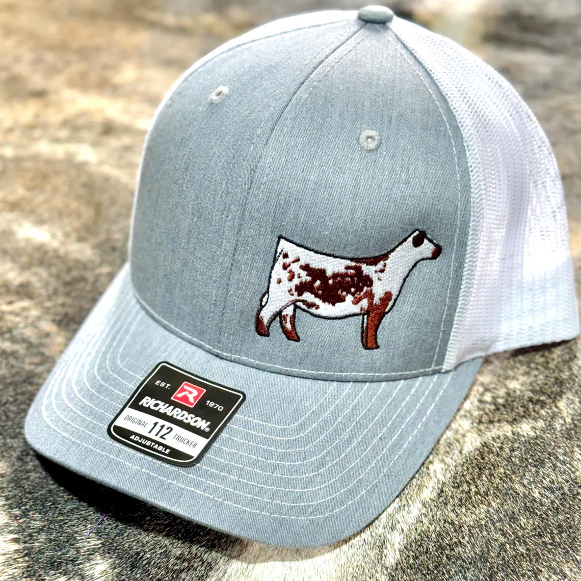 Red and white trucker hat with a red Speckle Park embroidered on the front. The hat has a Richardson 112 logo on the side.