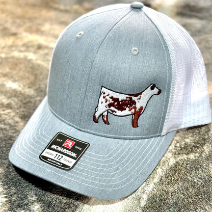 Red and white trucker hat with a red Speckle Park embroidered on the front. The hat has a Richardson 112 logo on the side.