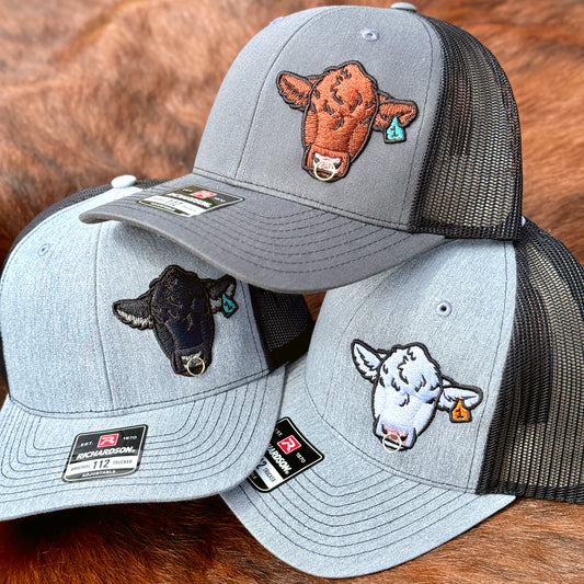 Three Richardson 112 hats featuring embroidered Angus, Red Angus, and Charolais bull heads with real metal rings installed into the bulls noses.
