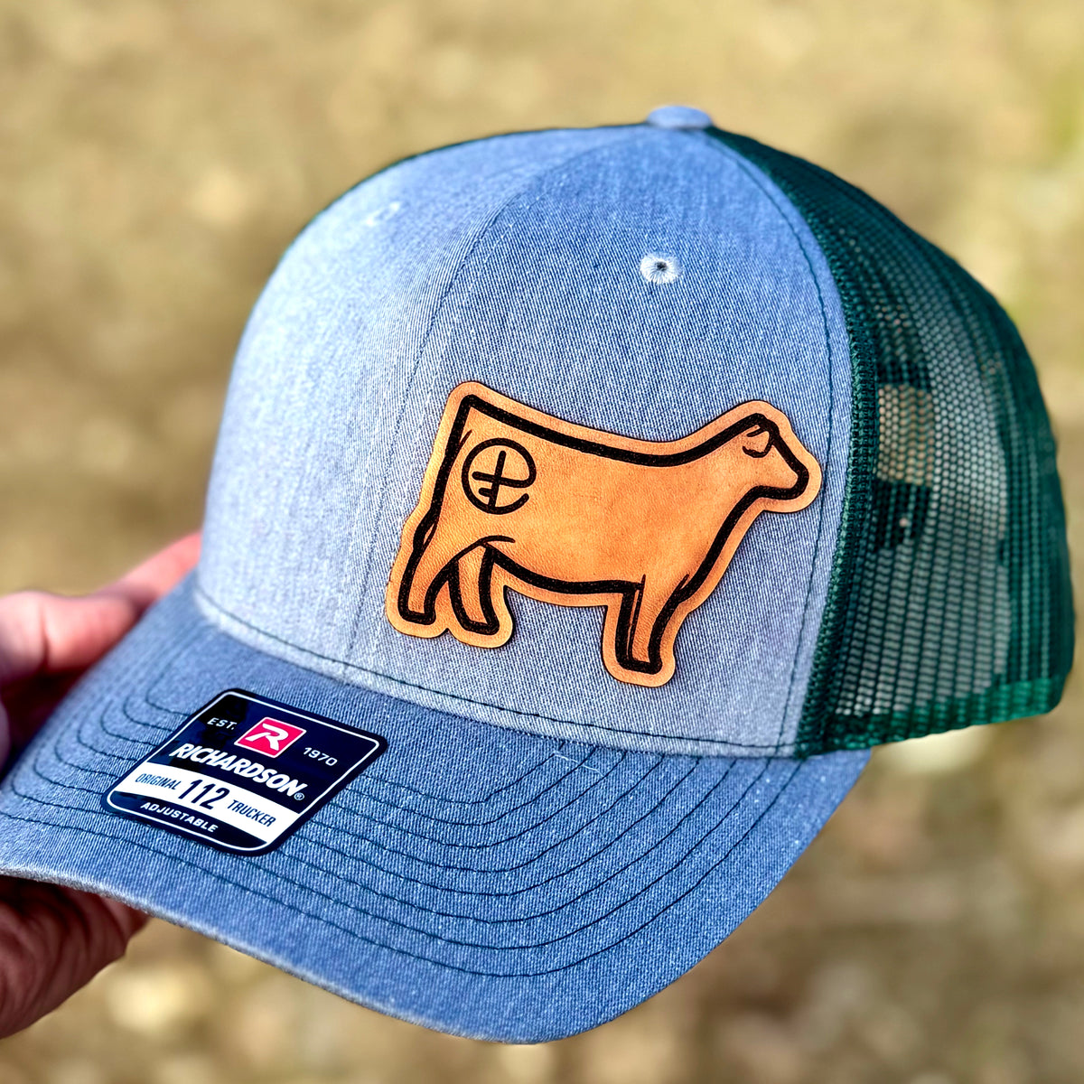 Genuine leather patch of a show heifer with a brand on the hip, on a Richardson 112 hat.