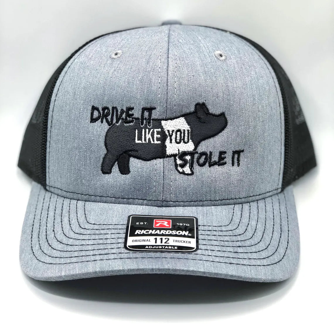 Embroidered trucker hat featuring the phrase Drive It Like You Stole It, designed for show pig exhibitors, livestock show enthusiasts, and FFA & 4-H members. Structured fit with a breathable mesh back and adjustable snapback closure.