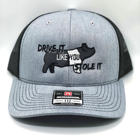 Embroidered trucker hat featuring the phrase Drive It Like You Stole It, designed for show pig exhibitors, livestock show enthusiasts, and FFA & 4-H members. Structured fit with a breathable mesh back and adjustable snapback closure.