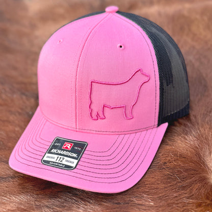 Pink and black hat featuring a raised 3D embroidered design of a pink outline of a show steer.