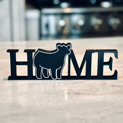 Freestanding tabletop or shelf decor reading the word "Home" with a show steer replacing the "O". Perfect for show cattle enthusiasts or those who love farmhouse decor.