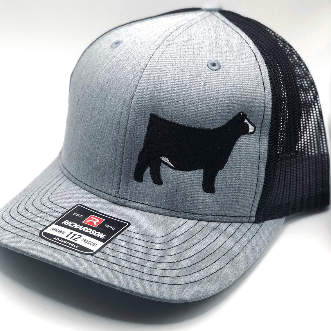 Close-up of Simmental cattle embroidery on a trucker hat, showcasing high-quality stitching and durable fabric for farm and casual wear
