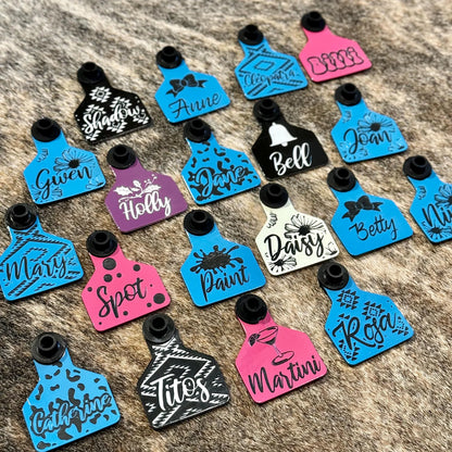 A collection of colorful, laser-engraved ear tags for sheep, goats, and pigs, featuring customizable designs and geometric patterns. Each tag displays personalized text, making them ideal for livestock identification or adding flair to show animals.