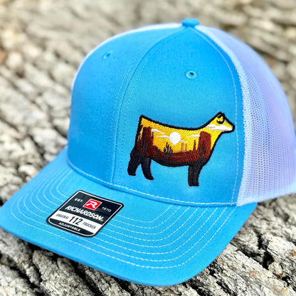 Embroidered hat of a desert scene in the silhouette of a show heifer