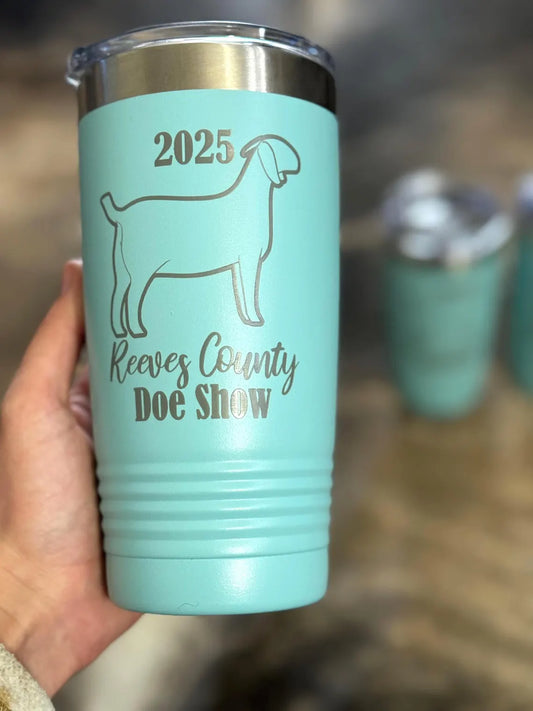 Turquoise tumbler with '2025 Reeves County Doe Show' text and show goat illustration, held by a hand.