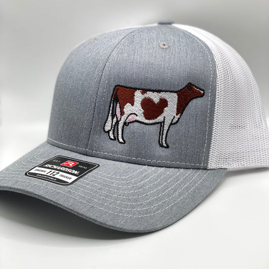 Embroidered trucker hat featuring a detailed Holstein cow design. The cap has a structured front, breathable mesh back, and an adjustable snapback closure. Perfect for dairy farmers, livestock showmen, or anyone passionate about the dairy industry.