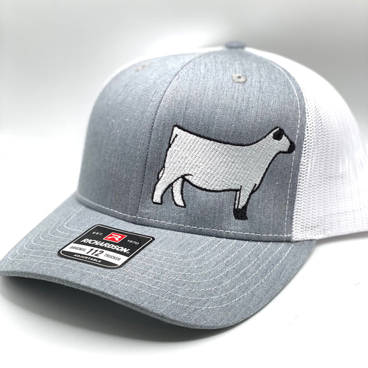 A custom embroidered trucker cap featuring a detailed White Park cow silhouette on the front panel. The hat is available in two color combinations: grey with black mesh and grey with white mesh. Offered in both adult and youth sizes, this cap is designed for livestock enthusiasts of all ages. Each hat is individually embroidered in-shop, ensuring high-quality craftsmanship.