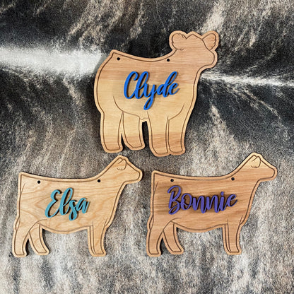 Three wooden stall signs with custom painted names for county fair or livestock shows.