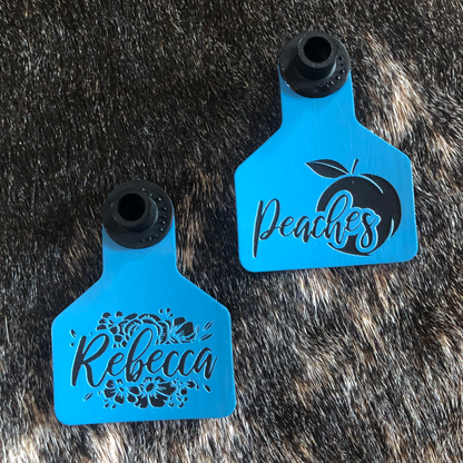 A collection of colorful, laser-engraved ear tags for sheep, goats, and pigs, featuring customizable designs and geometric patterns. Each tag displays personalized text, making them ideal for livestock identification or adding flair to show animals.