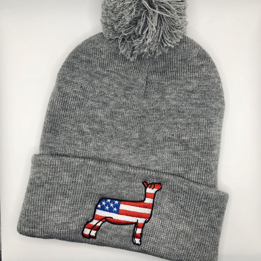 American Flag Show Sheep Beanie featuring an embroidered sheep design with an American flag. The knit beanie is available in black, dark grey, light grey, and heather cardinal, with an optional pompom on top.
