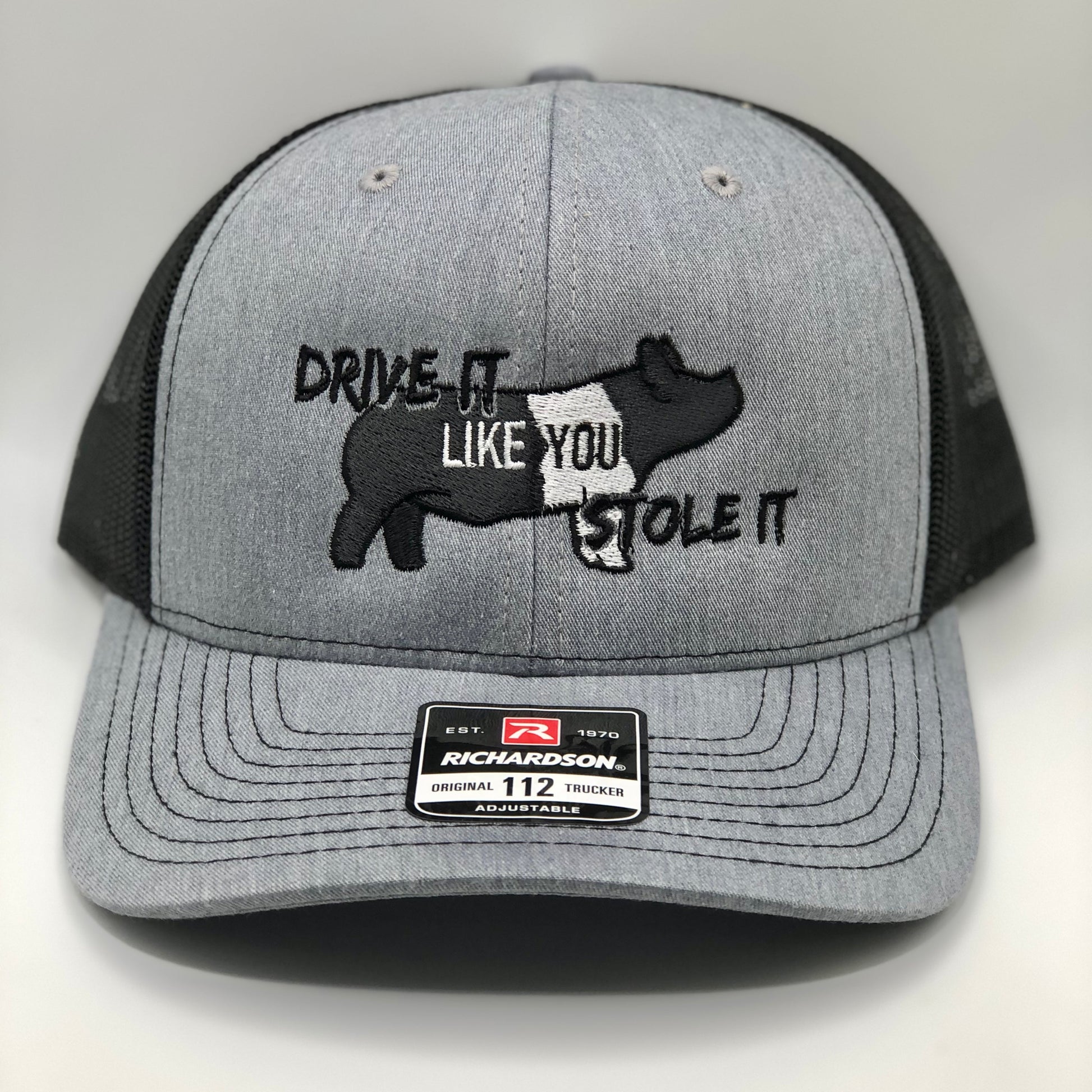 Embroidered trucker hat featuring the phrase &quot;Drive It Like You Stole It,&quot; designed for show pig exhibitors, livestock show enthusiasts, and FFA & 4-H members. Structured fit with a breathable mesh back and adjustable snapback closure.