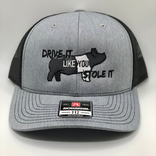 Embroidered trucker hat featuring the phrase &quot;Drive It Like You Stole It,&quot; designed for show pig exhibitors, livestock show enthusiasts, and FFA & 4-H members. Structured fit with a breathable mesh back and adjustable snapback closure.